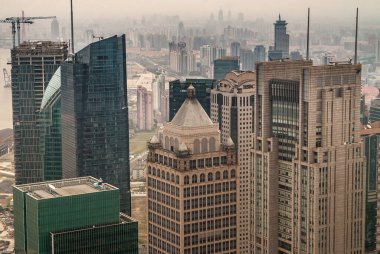 Shanghai, Pudong, Lujiazui, Çin - 4 Mayıs 2010: HSBC binası kısmen diğer kahverengi taş ve yeşil cam gökdelenlerin arasında gizlenmiş, ufuktaki diğer gökdelenlerin üzerinde sis var..