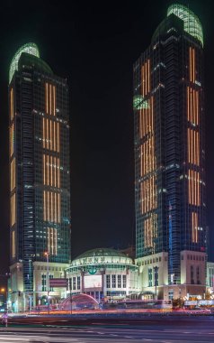 Şangay, Xuhui, Çin - 3 Mayıs 2010: Grand Gateway ikiz kuleleri ve AVM 'nin gece kapanışı, hepsi renkli ışıklandırılmış. Yolda trafik lambası çizgileri.