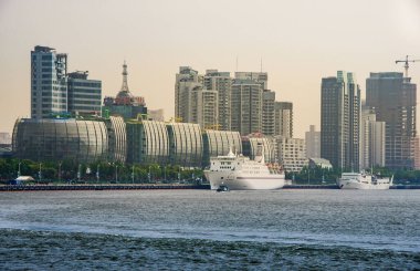 Şangay, Pudong, Lujiazui, Çin - 4 Mayıs 2010: mavimsi Huangpu Nehri boyunca beyaz gemisi olan Uluslararası Gemi Terminali 'nin cam binaları. Gümüş gökyüzünün altındaki yüksek binalar.