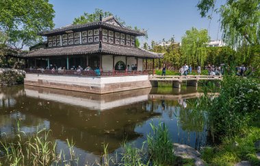Suzhou Çin - 3 Mayıs 2010 Mütevazı Yöneticiler Bahçesi. Çin mimarisinin merkezi kahverengi-beyaz yapısı, mavi gökyüzünün altında yeşil yapraklarla çevrili gölette kurulmuştur. Mevcut insanlar.