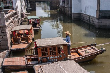 Suzhou China - 3 Mayıs 2010: Kahverengi ahşap taksiler ve kaptanlar yeşil su kanalı boyunca yanaşma noktasına yanaştılar. Yan yana evler..