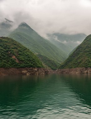 Wuchan, Çin - 7 Mayıs 2010: Daning Nehri 'ndeki Ejderha Kapısı Boğazı. Zümrüt yeşili suyun üzerinde, bulanık bulutlu, çoklu uzun yeşil dağların portresi..