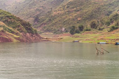 Wuchan, Çin - 7 Mayıs 2010: Daning Nehri üzerindeki Dicui Vadisi. Tarım arazisi ve dağlar arasında sıkışmış Inham manzarası, önünde gri-yeşil su ile balık kalem çubukları ile.