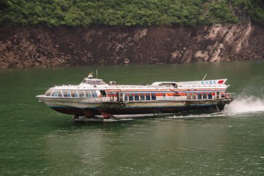 Baidicheng, Çin - 7 Mayıs 2010: Qutang Gorge, Yangtze Nehri. Meteor hızında, roket gibi, paslı beyaz yolcu feribotu yeşil su üzerinde kahverengi kayalık kıyı şeridi ve biraz yeşil bitki örtüsü..