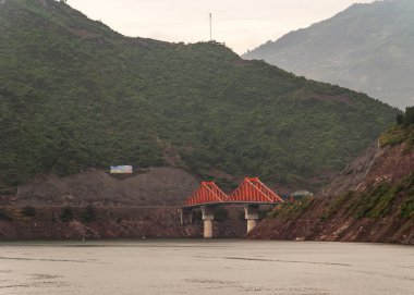 Shengli Caddesi, Çin - 6 Mayıs 2010: Yangtze Nehri 'ndeki Xiling geçidi. Kırmızı köprü bağlantıları X210 ve X239 yollarının yeşil suların üzerindeki yeşil yapraklarla kaplı dağların kapatılması.