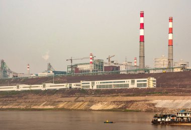 Chongqing, Çin - 8 Mayıs 2010 Yangtze Nehri. Elektrik santrali bacaları ve kahverengi toprak sahil şeridi üzerinde fabrikalar açık mavi gökyüzünün altında geniş kahverengi suyun arkasında.