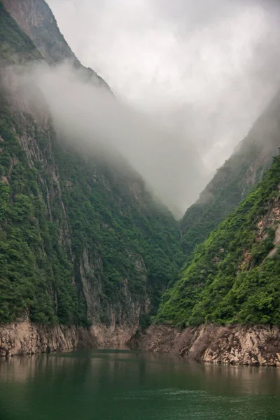 湖北省 2010年5月7日 長江の呉峡 エメラルドグリーンの水の後ろの狭い峡谷の緑に覆われた山の崖に沿って白い霧が降ります — ストック写真