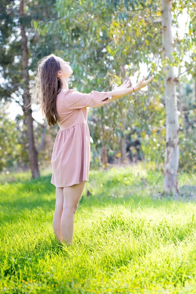 Young woman raising hands meditation pray towards sun.