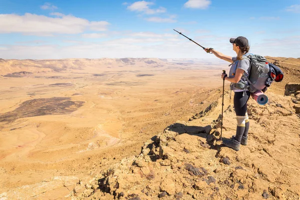 Ung kvinna turist backpacker stående söker Visa öken berg. — Stockfoto