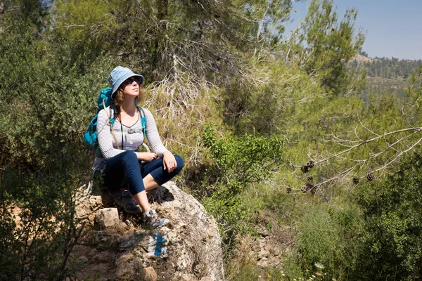 Kadın turist backpacker oturma dinlenme taş orman hiking seyahat.