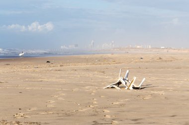 Kirliliği plaj deniz kıyısında çöp plastik sandalye şehir manzarası. 