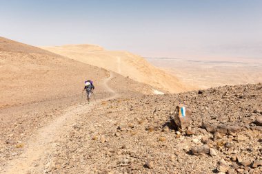 Hiking dolaşan backpacker adam tırmanış dağ çöl iz.