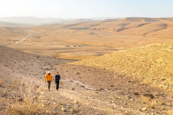 Par backpackers promenader stigande hill Negev-öknen, Israel. — Stockfoto