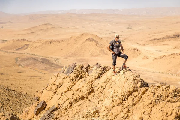 Backpacker tourist standing desert mountain cliff ridge edge landscape
