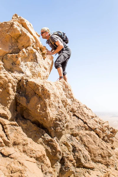 Backpacker tourist climbing desert mountain cliff ridge edge landscape