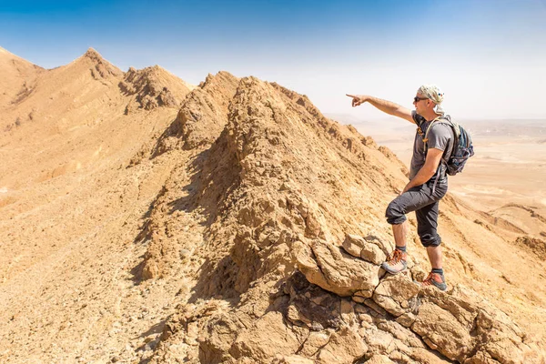 Backpacker tourist standing desert mountain cliff ridge edge landscape