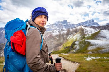 Sırt çantalı mutlu genç bir turist dağ yamacında tek başına dikiliyor, kameraya bakıyor, portre, manzara manzarası, Güney Tyrol Alpleri İtalya 'da tek başına Avrupa turizmi yapıyor..