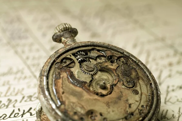 Rusted antique pocket watch on an old notebook