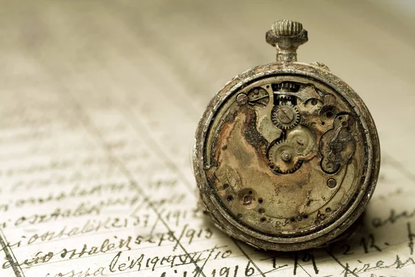 Rusted antique pocket watch on an old notebook — Stock Photo, Image