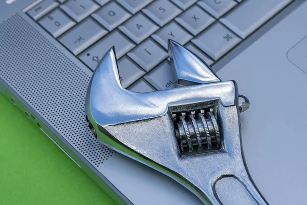 Adjustable wrench next to a silver laptop. Computer service, maintenance theme. — 스톡 사진