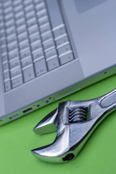 Adjustable wrench next to a silver laptop. Computer service, maintenance theme. — 스톡 사진