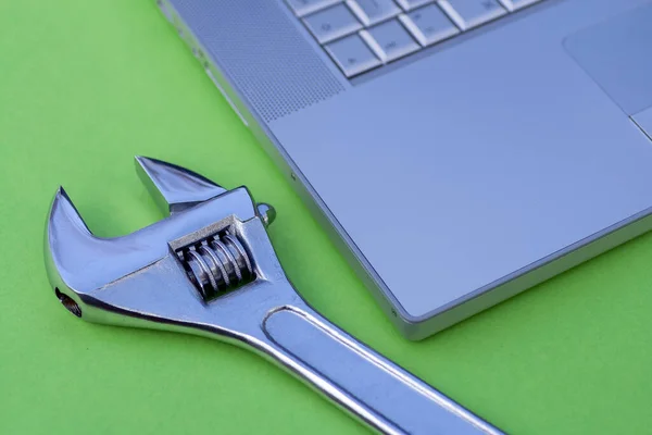 Adjustable wrench next to a silver laptop. Computer service, maintenance theme. — 스톡 사진