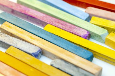 Beyaz arkaplanda renkli pastel boyaların yakın plan görüntüsü.