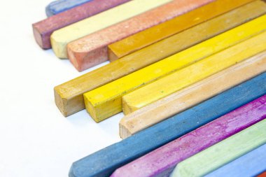 Beyaz arkaplanda renkli pastel boyaların yakın plan görüntüsü.