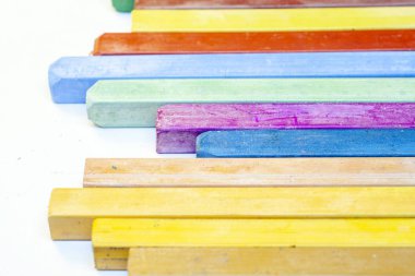 Beyaz arkaplanda renkli pastel boyaların yakın plan görüntüsü.