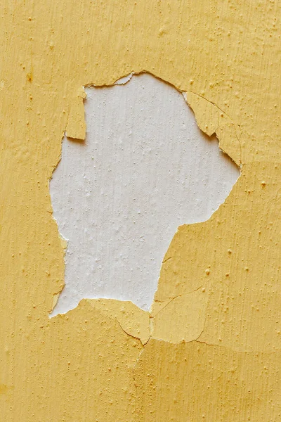 Old yellow paint is peeling off the wall.