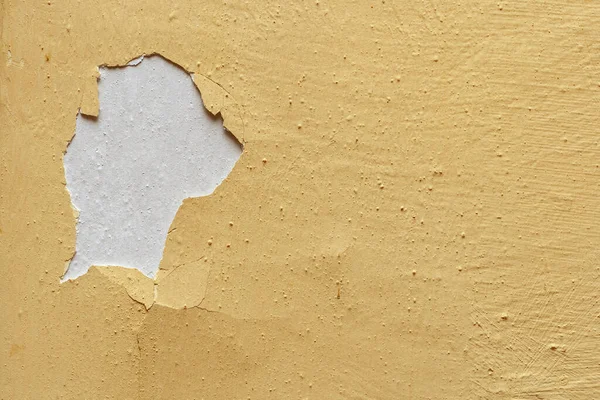 Old yellow paint is peeling off the wall.