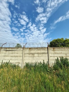 Beton çitin üzerindeki dikenli tel.