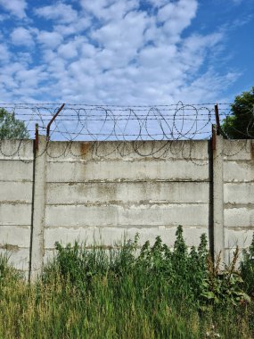Beton çitin üzerindeki dikenli tel.