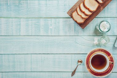 Dilimlenmiş bir pasta ve porselen bir fincan çayla saf ahşap arka plan.