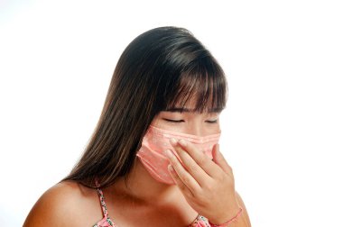 Maske takan Asyalı kız, öksürüyor ve gözlerini kapıyor.