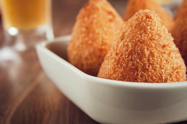 Brezilya usulü iştah açıcı. Kızarmış Coxinha de Frango. Yanında da bir bardak bira.