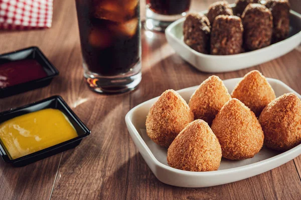 Brezilya aperatifi kızarmış Coxinha de frango, kibbe ve iki bardak meşrubat.
