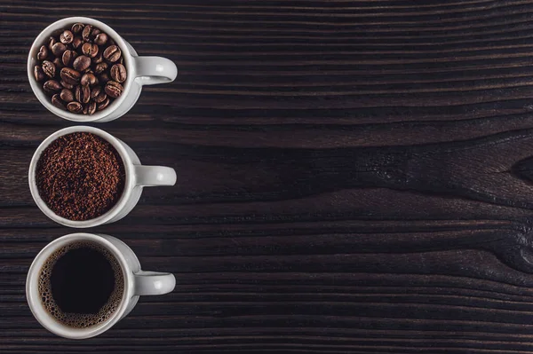 Brezilya kahvesi sıvı, toz ve fasulye siyah bir ahşap üzerinde.