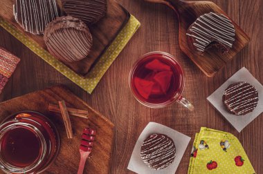 Tahta masanın üzerinde porselen bir fincan çay, bal arısı ve tarçınlı, ısırılmış ballı kurabiye.