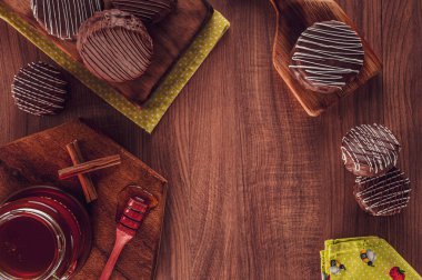 Tahta masanın üzerinde porselen bir fincan çay, bal arısı ve tarçınlı, ısırılmış ballı kurabiye.