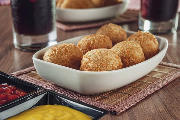 Brezilya mezesi, kızarmış peynirli kroket, hardal ve ketçaplı Bolinha de queijo.