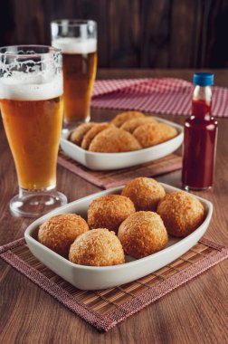 Brezilya aperatifi bol yağda kızartılmış peynirli kroket ve iki bardak bira ve acı biber sosu Bolinha de queijo.