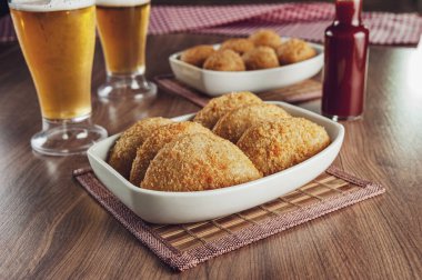 Brezilya aperatifi bol yağda kızartılmış biftek kroketi iki bardak bira ve kırmızı biber sosu - risolis de carne