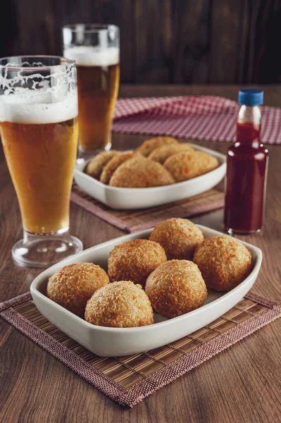 Brezilya aperatifi bol yağda kızartılmış peynirli kroket ve iki bardak bira ve acı biber sosu Bolinha de queijo.