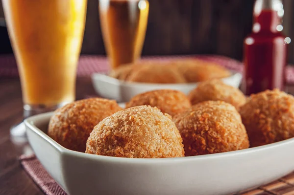 Brezilya aperatifi bol kızarmış peynirli kroket ve iki bardak bira - Bolinha de queijo