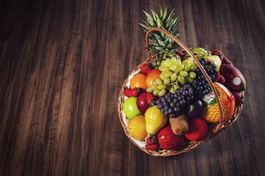 Tahta arka planda sepet ve taze meyve.