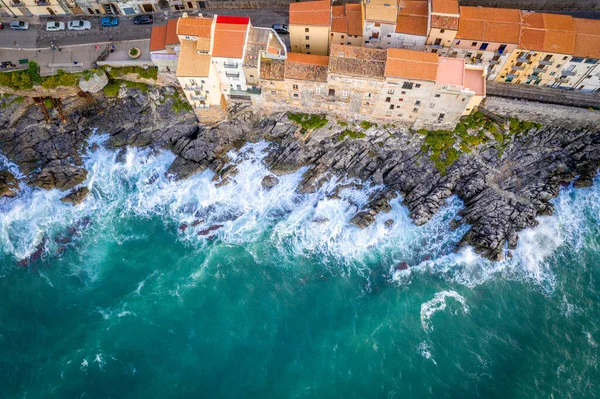 Αεροφωτογραφία της βραχώδους ακτής και των σπιτιών του Cefalu από τη θάλασσα με θυελλώδη και θυελλώδη καιρό. Μεγάλα κύματα χτυπούν τις πέτρες. Σικελία, Ιταλία — Φωτογραφία Αρχείου