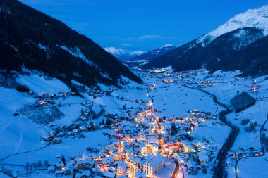 Avusturya 'nın Neustift kasabasında kış gecesi manzarası. Şehir merkezinin ve kilisenin havadan görüntüsü. Evlerin ve trafik ışıklarının gece aydınlanması. Tyrol, Stubai Vadisi