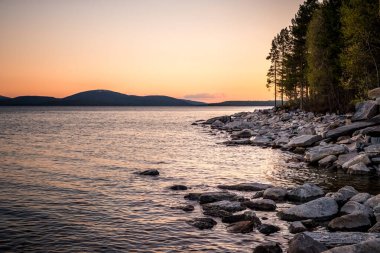 Günbatımında Beyaz Deniz kıyısında taşlar. Donmuş su, yaz, beyaz geceler.