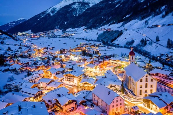 Winternachtelijk stadsgezicht in het Oostenrijkse Neustift. Uitzicht vanuit de lucht op het centrum en de kerk. Nachtverlichting van huizen en verkeerslichten. Tirol, Stubai-vallei — Stockfoto